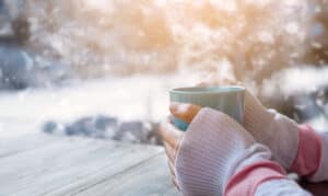 Kvinde varmer sine kolde hænder over en kop varm te